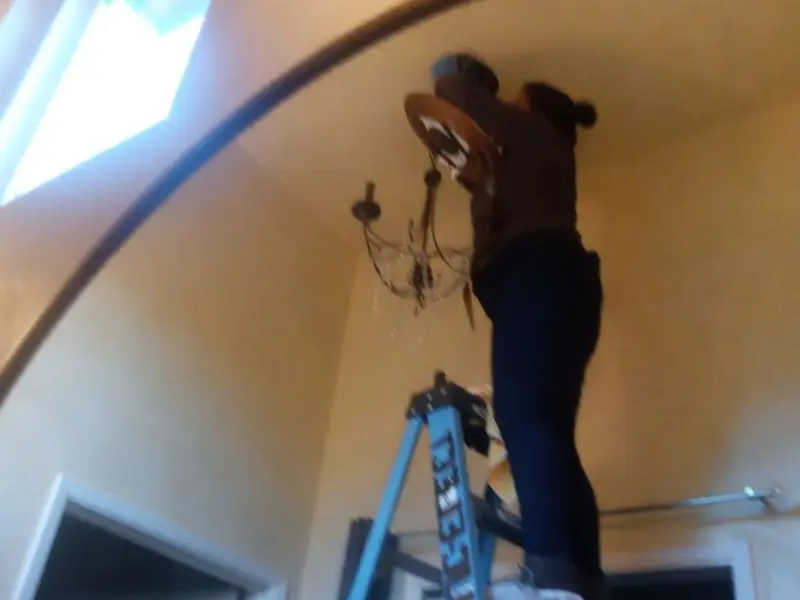 Electrician installing a chandelier in a Selbyville residence